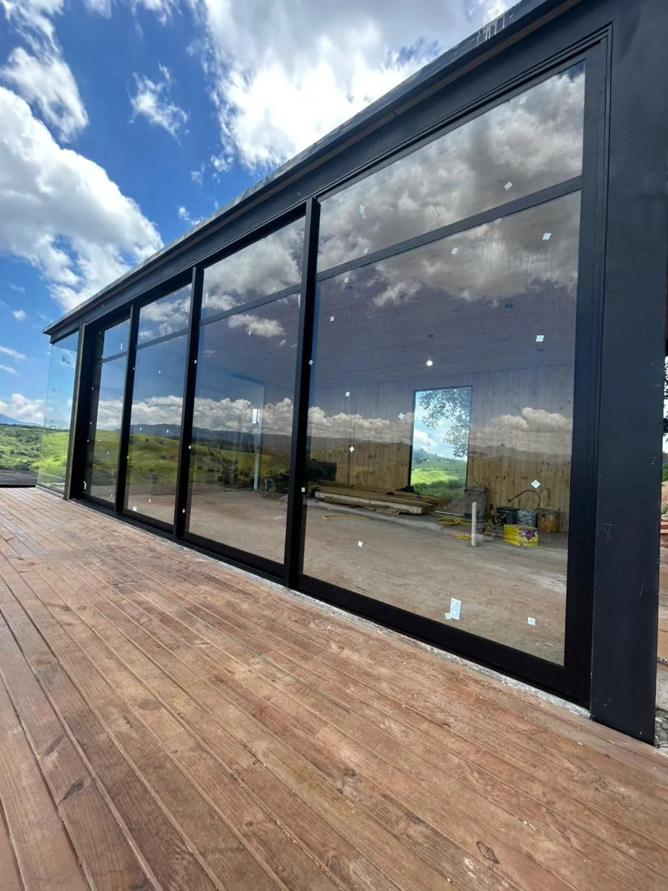 Área gourmet envidraçada com deck de madeira e vista aberta